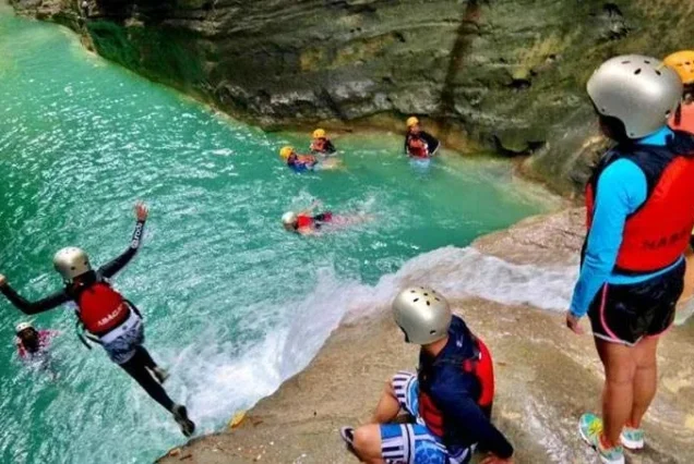 Travelers navigating waterfalls and rocky canyons during a Badian canyoneering adventure.