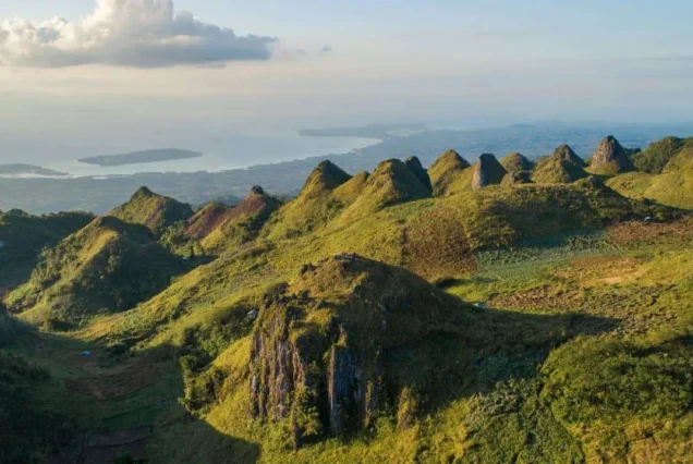 Scenic view of Osmeña Peak in Dalaguete, Cebu, surrounded by jagged hills and lush green landscapes.