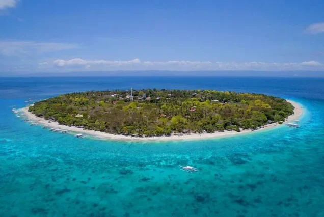 Balicasag Island in Bohol, Philippines, featuring crystal-clear turquoise waters, tropical scenery, and a beautiful island coastline.