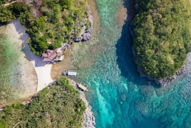 Natago Beach in Guimaras, featuring a secluded tropical shoreline surrounded by lush greenery and clear blue waters.