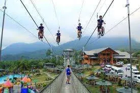 Visitors enjoying the sky bicycle and hanging bridge at Campuestohan Highland Resort, with mountain views in the background.