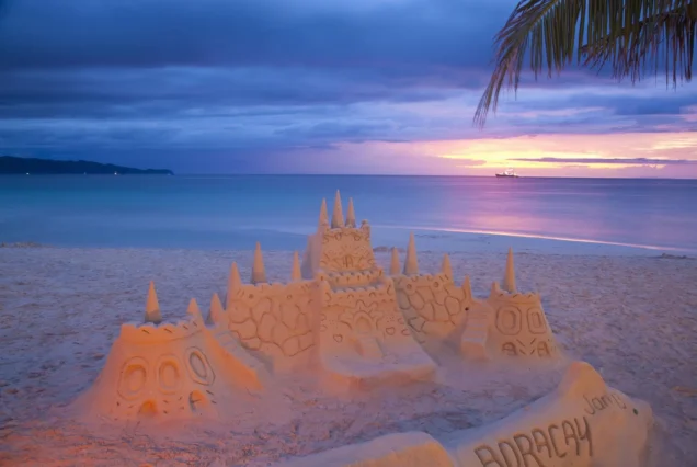 Sand castle on White Beach in Boracay, Aklan, with the tropical beach and clear blue sea in the background.